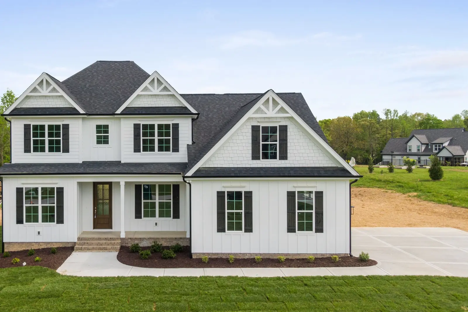 New white farmhouse-style two-story home with board-and-batten siding and a dark shingle roof